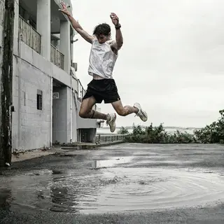 A man captured mid-jump over a puddle, body in the air with 