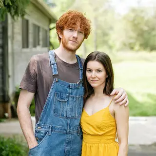 Two friends posing: one tall with curly red hair in denim ov