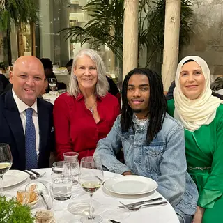 Four people at a dinner table: a bald man in a suit, a woman