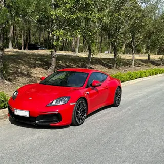 A bright red sports car parked on a gray asphalt road — the 