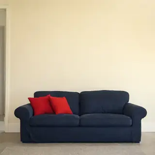 A minimalist room with walls in #F5E6CC (warm cream), a sofa