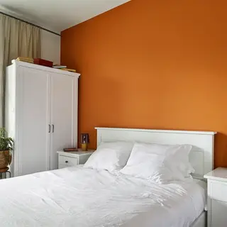 A bedroom wall painted in #FF6B35 (burnt orange) with white 