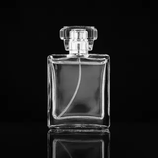 A clear glass perfume bottle on a reflective black surface w