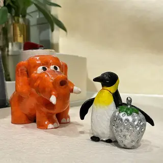 An orange elephant, a yellow penguin, and a silver strawberr