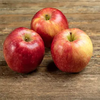 Exactly 3 red apples arranged on a wooden table