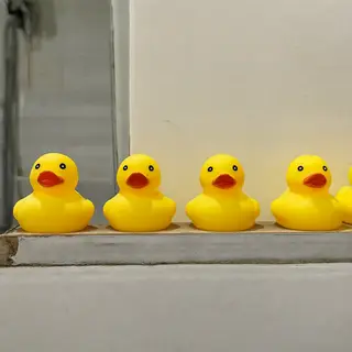 Exactly 5 yellow rubber ducks sitting in a row on a bathroom