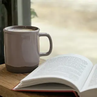 A coffee mug next to an open book on a desk