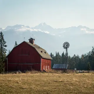 A landscape with a red barn in the foreground at large scale