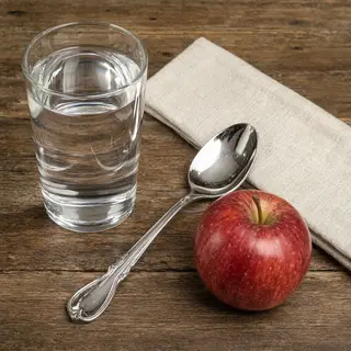 A still life on a wooden table featuring a clear glass of wa