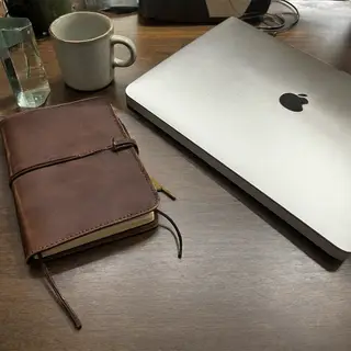 A workspace desk with a brushed aluminum laptop, a leather-b
