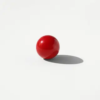 A red sphere on a white surface with a single shadow cast to