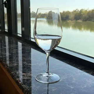 A crystal wine glass on a polished marble counter next to a 