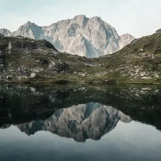 A mountain range reflected in a still alpine lake, with the 