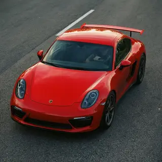 A bright red sports car parked on a gray asphalt road — the 