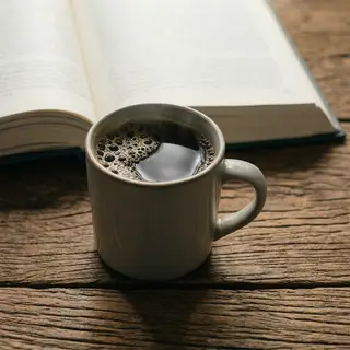 A coffee mug next to an open book on a desk