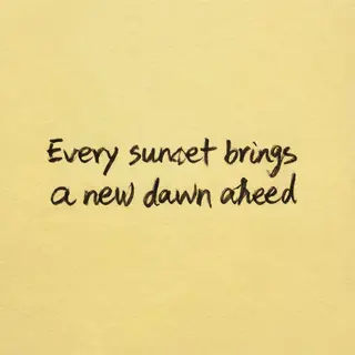 'Every sunset brings a new dawn ahead' written neatly on a p