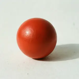 A red sphere on a white surface with a single shadow cast to
