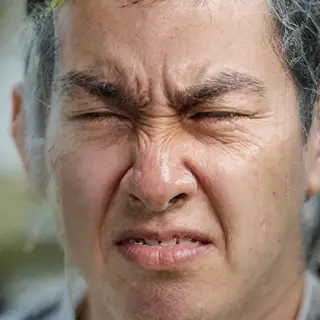 A close-up of a person's face showing clear disgust, nose wr