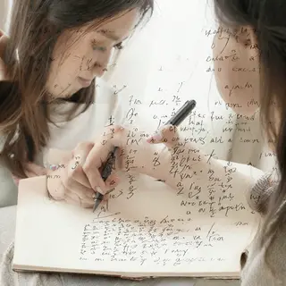 A woman writing in a notebook with a pen gripped correctly i