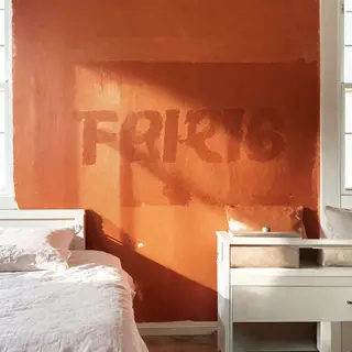 A bedroom wall painted in #FF6B35 (burnt orange) with white 