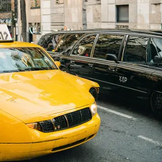 A yellow taxi and a black limousine parked next to each othe