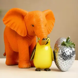 An orange elephant, a yellow penguin, and a silver strawberr