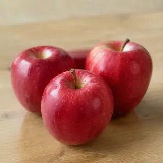 Exactly 3 red apples arranged on a wooden table
