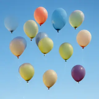 Exactly 11 colorful balloons floating against a clear blue s