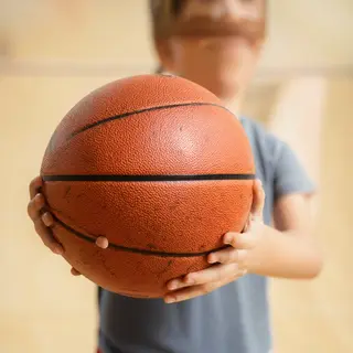 A child holding a basketball, both at correct relative sizes