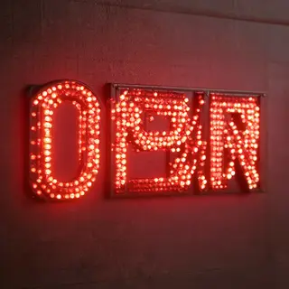 The word 'OPEN' displayed on a red LED sign with glowing pix