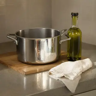 A kitchen counter with a stainless steel pot, a wooden cutti