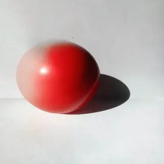 A red sphere on a white surface with a single shadow cast to
