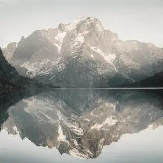 A mountain range reflected in a still alpine lake, with the 