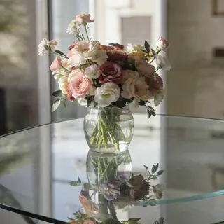 A vase of flowers on a glass table with a clear reflection v