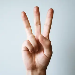 A person counting to three on their fingers, with index, mid