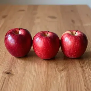 Exactly 3 red apples arranged on a wooden table