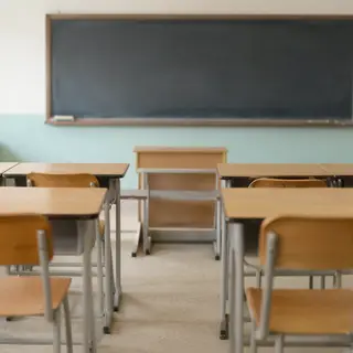 A classroom with desks and a chalkboard but no students
