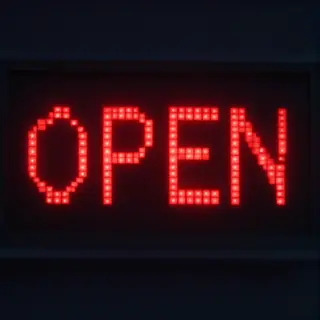 The word 'OPEN' displayed on a red LED sign with glowing pix