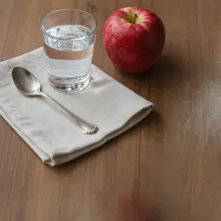 A still life on a wooden table featuring a clear glass of wa