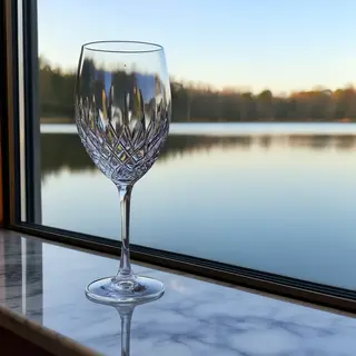 A crystal wine glass on a polished marble counter next to a 