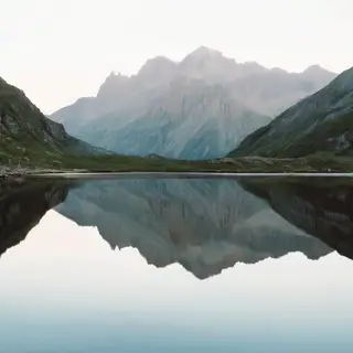 A mountain range reflected in a still alpine lake, with the 