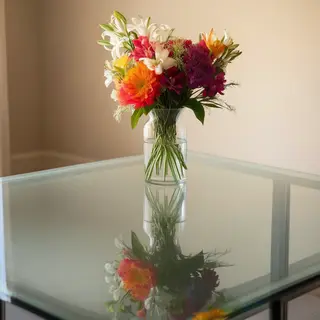 A vase of flowers on a glass table with a clear reflection v