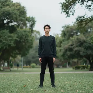 A person standing in a neutral pose in a park, full body vis
