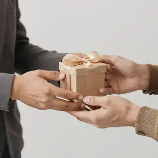 One person handing a small gift box to another person, both 