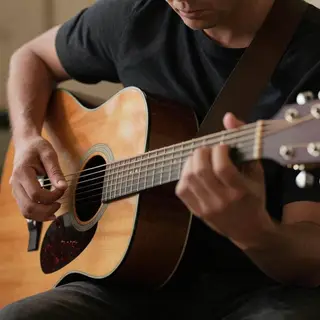 A person playing an acoustic guitar with left hand on the fr