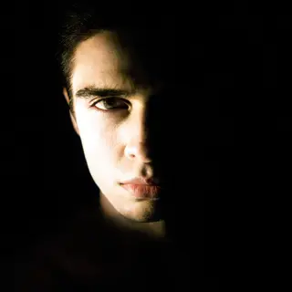 A portrait with dramatic split lighting — half the face brig