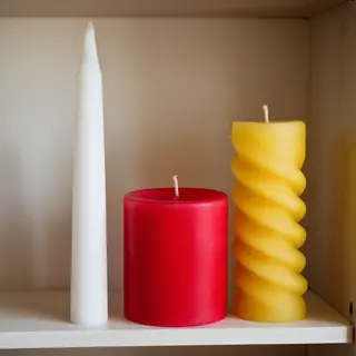 A tall thin white candle, a short fat red candle, and a medi