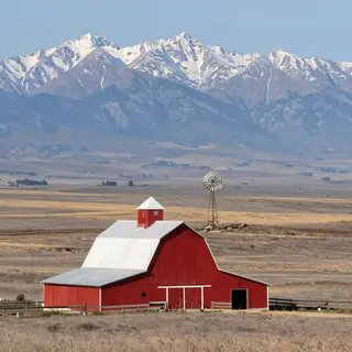 A landscape with a red barn in the foreground at large scale