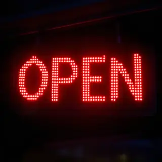 The word 'OPEN' displayed on a red LED sign with glowing pix