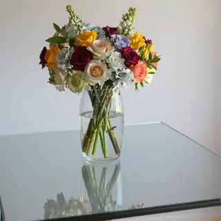A vase of flowers on a glass table with a clear reflection v